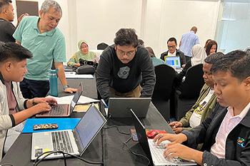 Part of the PAM-M team around a table on laptops