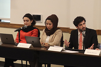 Three panelists at a table, with one speaking