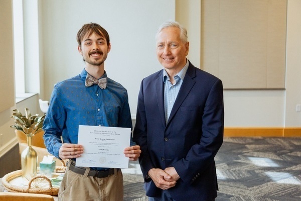 Award certificate, smiling with an older man in a blue suit.