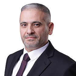 Man in suit and tie, looking directly at the camera with a serious expression.